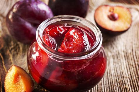 Abgefüllte Erdbeer-Ingwer-Marmelade in Gläsern auf einem Holzbrett