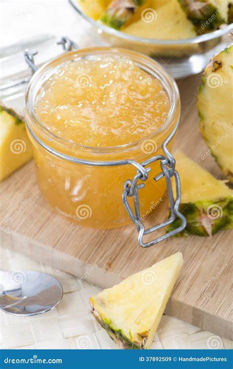 Angerichtete Ananas-Rosmarin-Marmelade im Glas neben frischer Ananas und Rosmarinzweigen