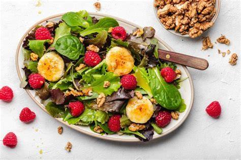 Angerichteter Salat mit warmem Ziegenkäse, Himbeeren und Walnüssen