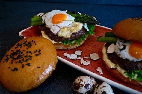 Angerichteter Wagyu Trüffel Burger mit grünem Spargel und Wachtelei
