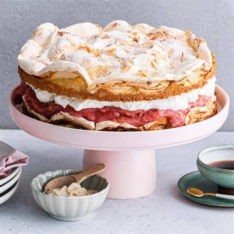 Angeschnittene Rhabarber-Biskuit-Torte mit Sahnetuffs und Rhabarberdeko