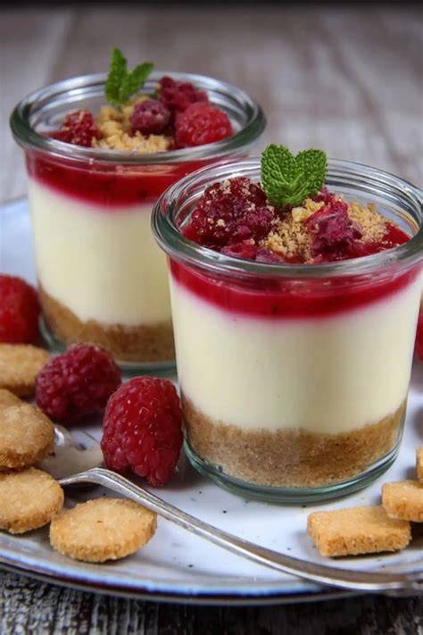 Anrichten: Käsekuchen im Glas mit Beeren und Minzblatt garniert