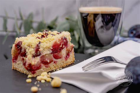 Anschnitt des saftigen Pflaumenkuchens ohne Streusel, serviert mit Sahne