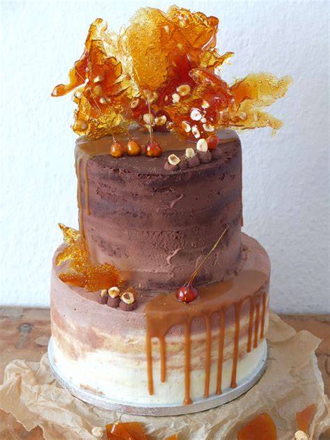 Anschnitt einer Karamell-Haselnuss-Torte mit Drip, Buttercreme-Tuffs und gerösteten Haselnüssen