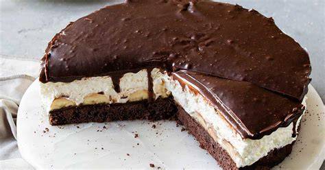 Anschnitt einer Nutella Bananen Torte auf einer Platte, dekoriert mit Haselnüssen