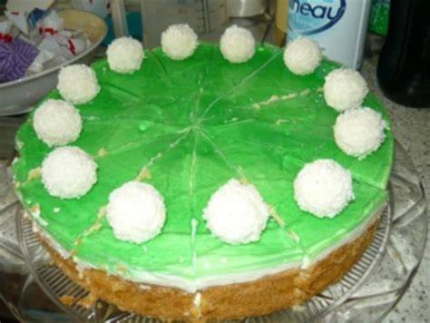 Anschnitt einer Waldmeister-Kokos-Torte mit grünem Spiegel und Raffaello-Deko