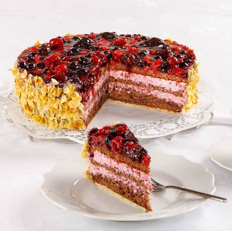 Anschnitt einer klassischen Waldfrucht Sahnetorte mit Sahneverzierung und frischen Beeren