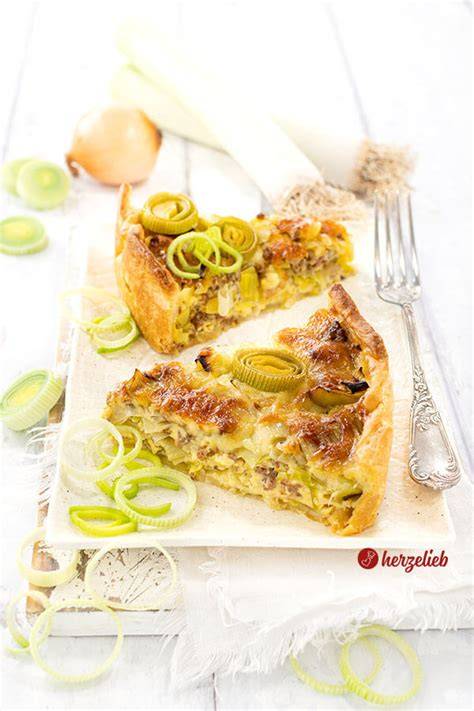 Anschnitt eines goldbraun gebackenen Lauchkuchens auf Blech mit Lauchringen und Speck