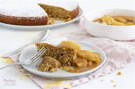Apfel Polenta Kuchen auf einer rustikalen Tafel, angeschnitten mit Äpfeln und einem Glas Milch