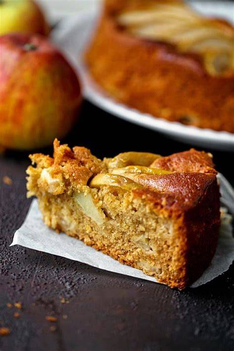 Apfel-Honig-Kuchen angerichtet auf rustikalem Holztisch, Zutaten (Äpfel, Honig, Mehl) daneben