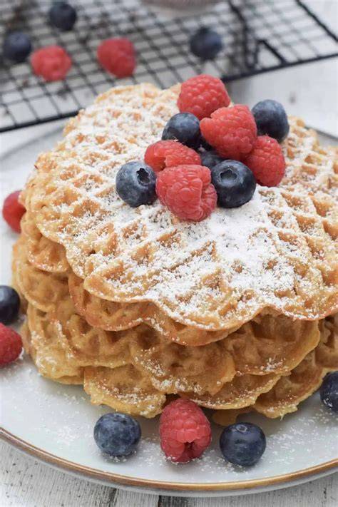 Apfel-Zimt-Waffeln auf Holzuntergrund mit frischen Äpfeln und Zimtstange