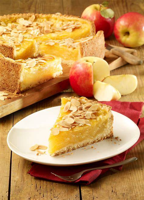 Apfelkuchen auf rustikalem Holztisch mit Äpfeln im Hintergrund