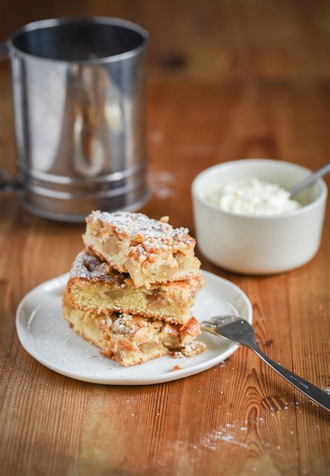 Apfelkuchen mit Nussboden auf einem Kuchengitter, bestäubt mit Puderzucker