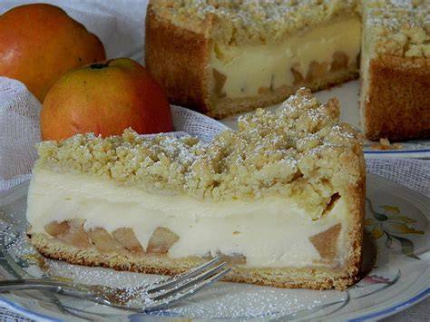 Apfelkuchen mit Vanillecreme und goldbraunen Streuseln auf Holzbrett, Zutaten rundum