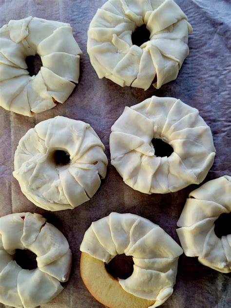 Apfelringe mit Blätterteig auf Backblech vor dem Backen