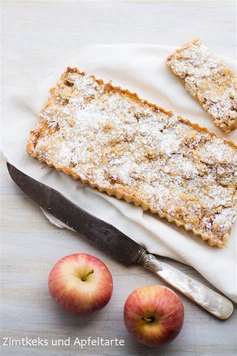Apfeltarte mit goldbraunen Streuseln und Apfelscheiben auf Holzbrett, herbstliche Stimmung