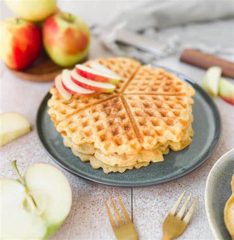 Apfelwaffeln auf einem Gitter, daneben geriebene Äpfel und Zimt