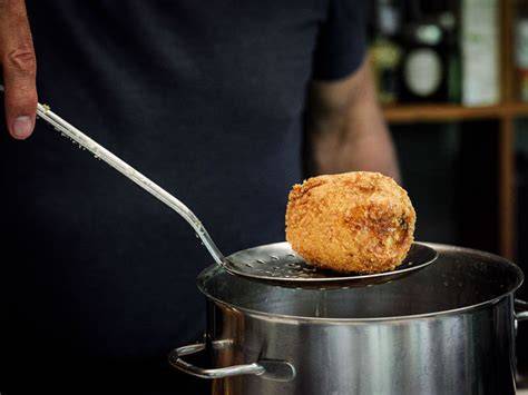 Arancini beim Frittieren in heißem Öl