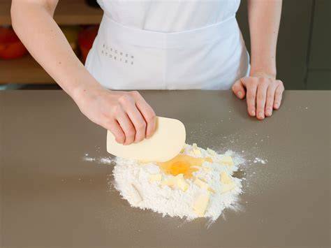 Arbeitsfläche mit Marzipan, Frischhaltefolie und Teigrollen