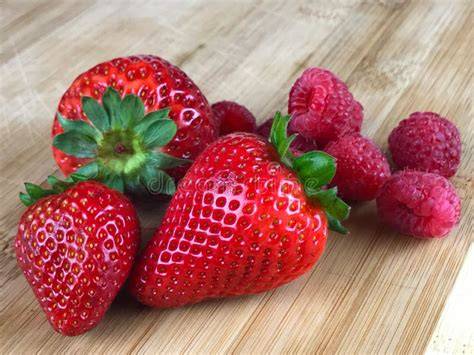 Aroniabeeren und Himbeeren auf einem Brett