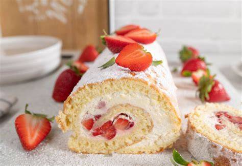Aufgerollte Biskuitrolle mit Puderzucker bestäubt und Erdbeeren als Garnitur
