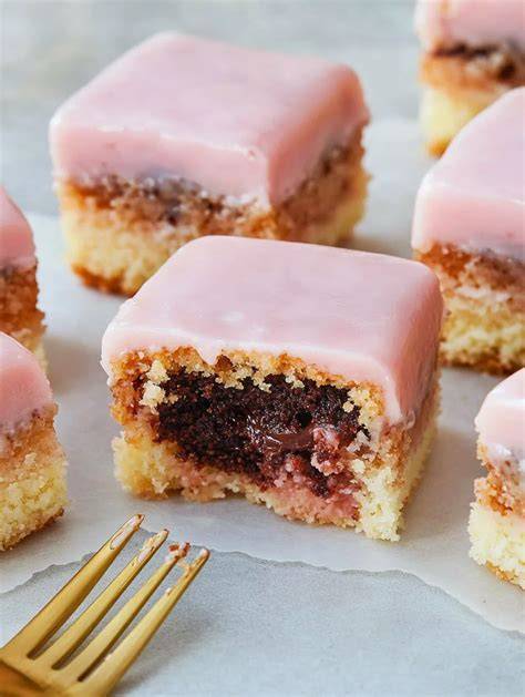 Aufgeschnittene Punschkrapfen mit Marmeladenschicht und rosa Glasur