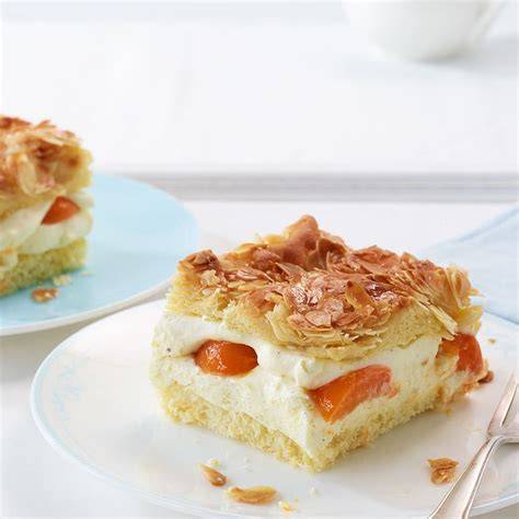 Aufgeschnittener Aprikosen-Bienenstich auf Teller, Nahaufnahme der Creme und Mandeldecke