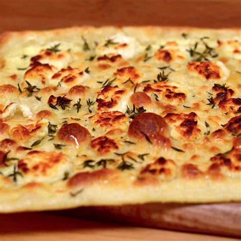 Aufgeschnittener Flammkuchen mit Honig beträufelt und mit Thymian garniert