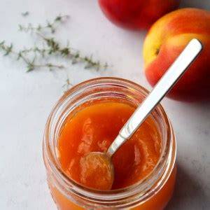 Aufgeschnittenes Glas Pfirsichmarmelade mit Löffel