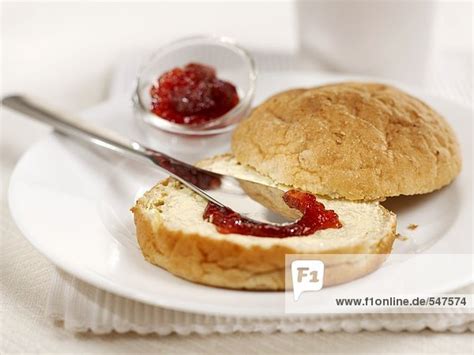Aufgeschnittenes Milchbrötchen mit Butter und Marmelade