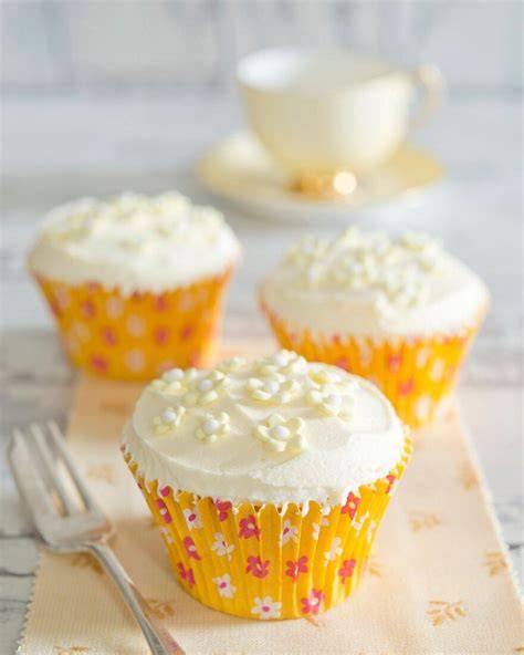 Aufgesetzte Fondant-Halbschalen auf Cupcakes mit kleinen Zuckerblumen