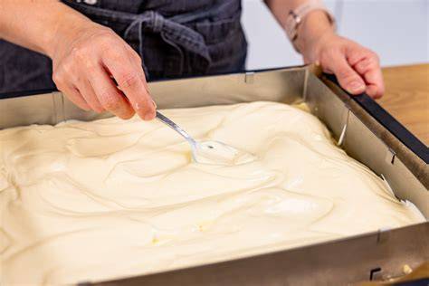 Aufgestrichene Schmandcreme auf Kuchenboden