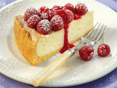 Aufgetaute Käsekuchenstücke auf Teller, frisch mit Fruchtsoße serviert