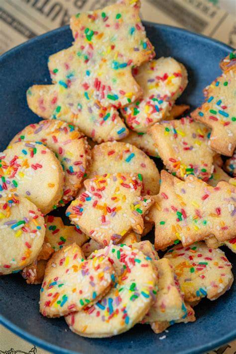 Ausgerollter Plätzchenteig, verschiedene Ausstechformen und bunte Streusel