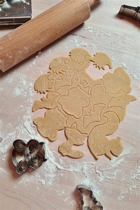 Ausgerollter Teig auf Arbeitsfläche mit Ausstechern und Kindern beim Backen