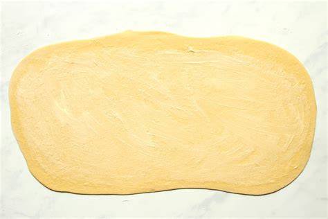 Ausgerollter Teig und ausgestochene Marzipanplätzchen