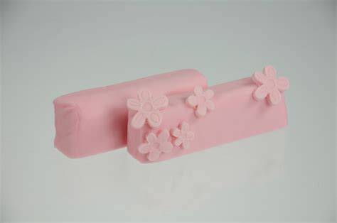 Ausgerollter babyrosa Fondant, zugeschnittene Herz-Elemente, Gold-Feenstaub als Akzent