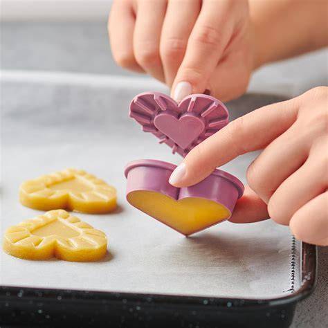 Ausstecher und Plätzchen in Herzform auf Backblech