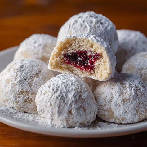 Backblech mit frisch gebackenen Mandelkugeln, einige im Puderzucker gewälzt