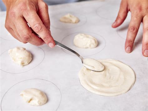 Baiser-Masse werden zu Kreisen auf Backpapier gestrichen