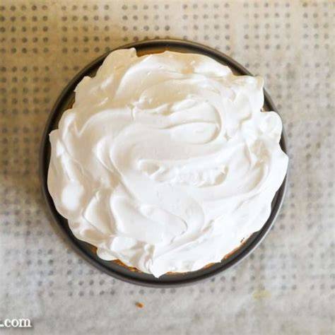 Baiserhaube wird mit Spatel auf den Kuchen gestrichen