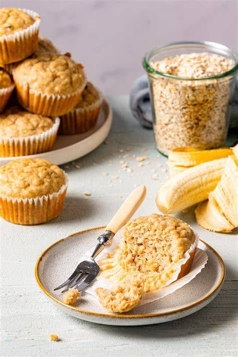 Bananenmuffins in Muffinförmchen, daneben Haferflocken und Datteln