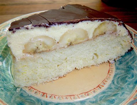 Bananentorte mit glänzendem Schokoguss und Sahnetupfen