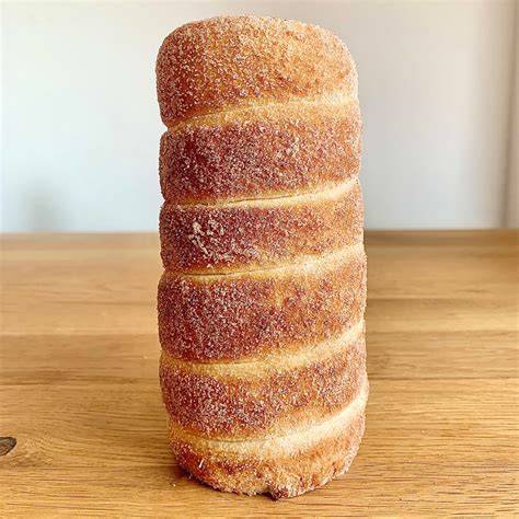 Baumstriezel auf Nudelholz, mit Zucker und Zimt bestreut, goldbraun gebacken
