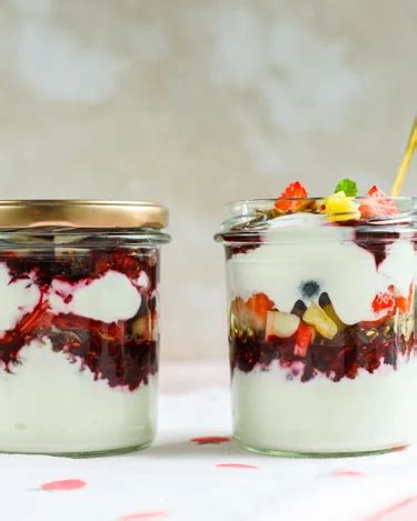 Beerenkompott mit Granola und Kokoscreme im Glas, sommerliche Dekoration