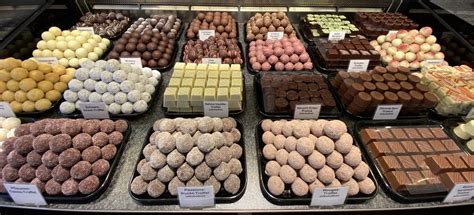 Beleuchtete Pralinentheke, zahlreiche bunte Pralinen, Besucher probieren und schauen interessiert