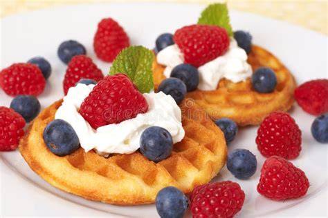 Belgische Waffeln, angerichtet mit Ahornsirup, Beeren und Sahne