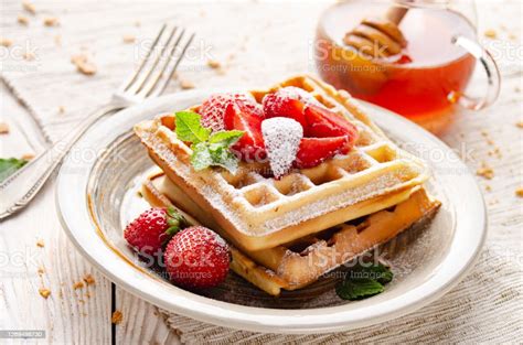 Belgische Waffeln auf Tellern mit Puderzucker und Erdbeeren