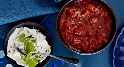 Bild einer Schüssel gehackter Chilischoten, Paprika und Tomaten, Kochtopf daneben
