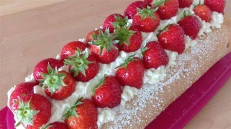 Biskuit-Baiser-Rolle dekoriert mit frischen Früchten und Puderzucker